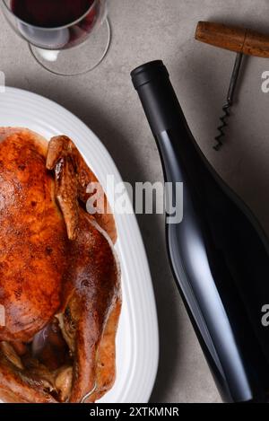 Flache Anordnung eines Esstisch mit einer Flasche Rotwein und gebratenem truthahn auf einem Teller. Die Flasche hat kein Etikett. Stockfoto