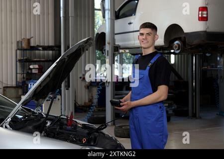 Junger Automechaniker, der in der Autowerkstatt Autodiagnostik macht Stockfoto