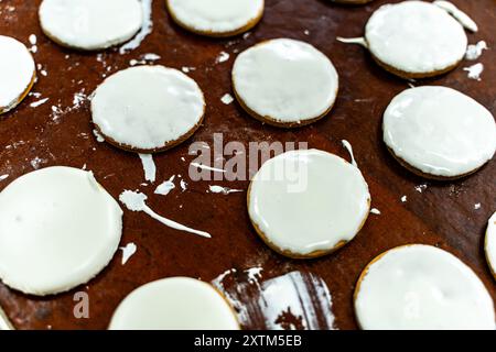 Plätzchen mit weißer Glasur auf einem Backblech. Herstellung von Keksen. Mini-Bäckerei oder industrielle Produktionslinie für Mehlprodukte. Hochwertige Fotos Stockfoto