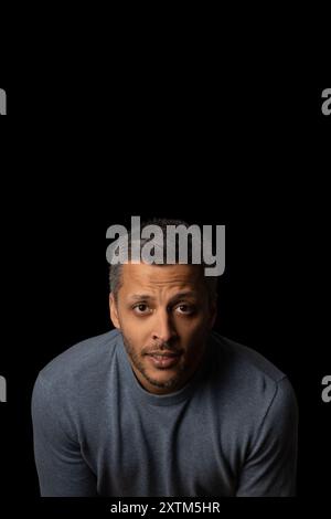 Ein Mann mit Bart und grauem Haar trägt ein blaues Hemd und schaut in die Kamera. Das Bild ist schwarz-weiß und verleiht ihm eine stimmungsvolle und dramatische Atmosphäre Stockfoto