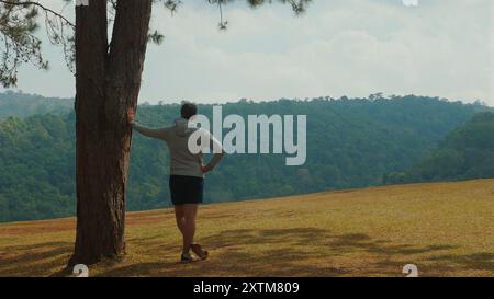 Der Mensch entspannt sich in der Natur, lehnt sich an den Baum und bewundert die Ruhe Stockfoto