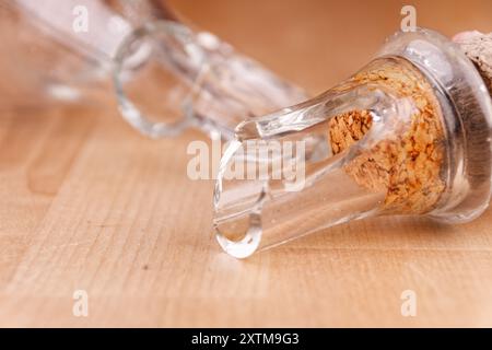 Kaputte Glasflasche mit Kork auf Holztisch, Nahaufnahme, kaputte Struktur Stockfoto