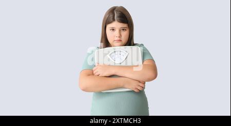 Traurige übergewichtige Mädchen mit Messskalen auf hellem Hintergrund Stockfoto