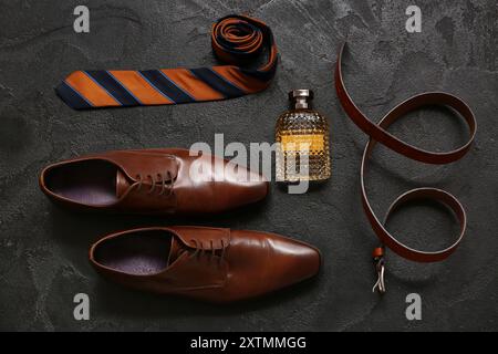 Set männlicher Accessoires mit Schuhen, Parfüm, Gürtel und Krawatte auf schwarzem Hintergrund. Draufsicht Stockfoto