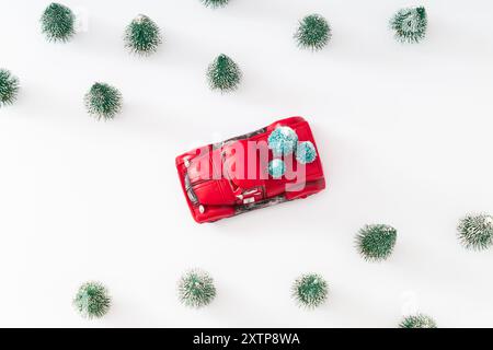 Kreatives Layout mit rotem Weihnachts-Retro-Truck und grünen Weihnachtsbäumen auf weißem Hintergrund. Minimales Weihnachts- und Neujahrskonzept. Stockfoto