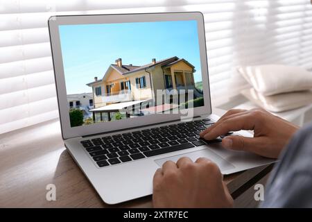 Mann sucht Haus auf der Immobilienmarkt-Website am Tisch, Nahaufnahme Stockfoto