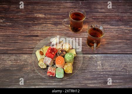 Ein Teller mit verschiedenen orientalischen Süßigkeiten und zwei Tassen heißem schwarzem Tee auf einem Holztisch. Draufsicht, flach. Stockfoto