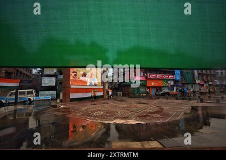 Srinagar, Jammu Und Kaschmir, Indien. August 2024. Die Menschen laufen in einem Regen, während der indische Premierminister Narendra Modi am Straßenrand auf einem großen Videobildschirm zu sehen ist, der den Independent Day in Srinagar, dem indianischen Kaschmir, am Donnerstag, den 15. August 2024 feiert. (Kreditbild: © Mubashir Hassan/Pacific Press via ZUMA Press Wire) NUR REDAKTIONELLE VERWENDUNG! Nicht für kommerzielle ZWECKE! Stockfoto