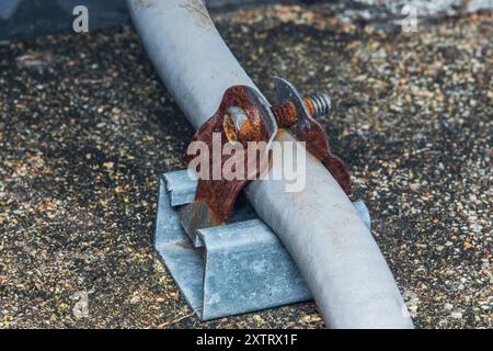 Rostige Metallklammer zur Befestigung des elektrischen Kabelkanals auf dem Dach. Stockfoto