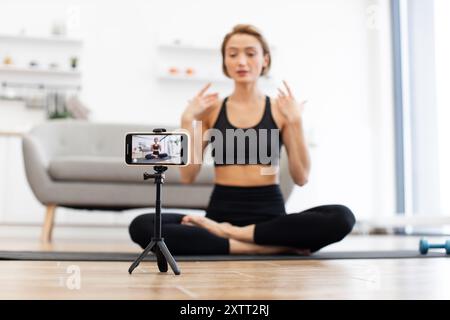 Yogalehrer nimmt virtuellen Fitnesskurs auf dem Smartphone auf Stockfoto