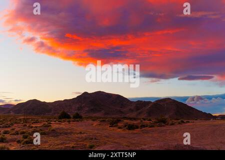 Spektakulärer Abendhimmel mit leuchtenden Orangen und Lila über zerklüfteten Bergketten in Kalifornien. Die dramatischen Wolken sorgen für einen atemberaubenden Wettkampf Stockfoto