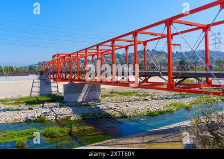 Los Angeles, Kalifornien - 21. April 2024: Hellrote Fußgängerbrücke über den LA River, die Wege im Elysian Valley, Frogtown, verbindet. Stockfoto