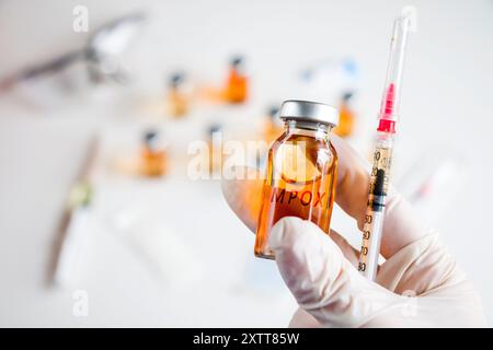 Mpox neuer Impfstoff in Ampullen und Flaschen, Nadel und Arzthänden mit Handschuh. Stockfoto