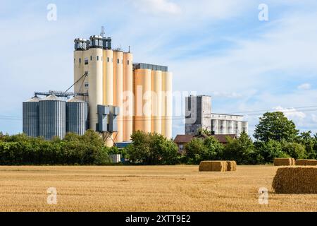 Zwei Getreideturmsilos auf dem Land mit Strohballen im Vordergrund an einem sonnigen Sommertag. Stockfoto