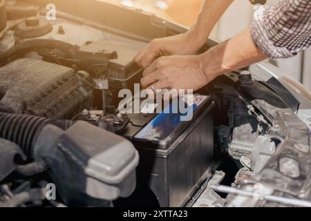 Nahaufnahme von Automechanikern, die die Batterie eines Autos überprüfen. Ein Mann schraubt eine Autobatterie ab. Reparatur und Austausch der Batterie. Stockfoto