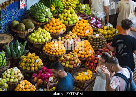 Touristen probieren einige der farbenfrohen frischen Früchte auf dem Markt Mercado dos Lavradores im Herzen von Funchal, Madeira, der am 6. August 2024 gesehen wurde. Stockfoto