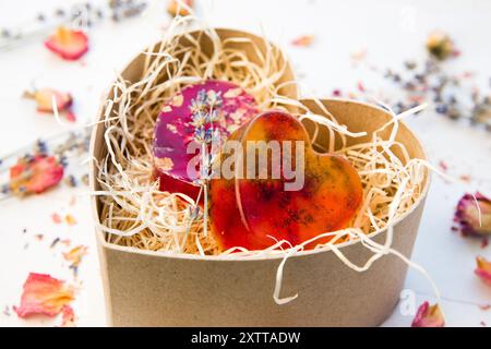 Handgemachte Seife mit kristallklarem Schmelz- und Gießseifengemisch. Gebrauchsfertige Seifen mit rosafarbenen und gelben Binden, Rosenblüten und Lavendelblüten. Stockfoto