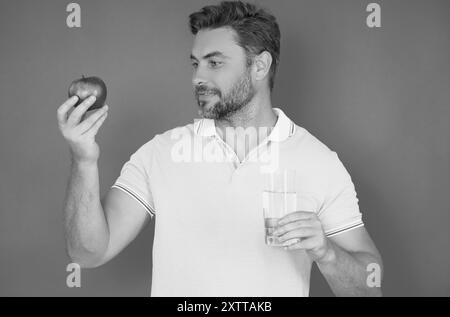 Ein Mann, der leckeren Apfel bastelt. Mann isst Apfel, Studioporträt. Frühstück am Morgen. Mann mit gesunden Zähnen, der Äpfel auf gelb isoliertem Hintergrund hält Stockfoto