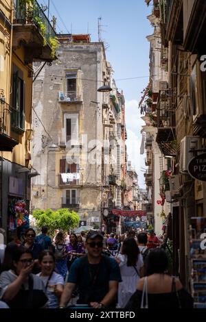 Touristen hektisch in einer typischen Straße in Neapel mit Drähten, die zwischen Gebäuden in Italien, Europa und den kommerziellen Straßen von Neapel verlaufen Stockfoto