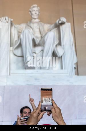 Washington DC, USA - 10. Oktober 2022: Touristen machen Fotos vor einer kolossalen Marmorstatue von Abraham Lincoln, die in einem großen Saal sitzt, umgeben von Stockfoto