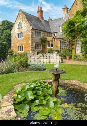 Kleiner Zierteich mit Brunnen Wasserlilien und Vogelbad, Coton Manor House and Gardens im Sommer, Northamptonshire, England, Großbritannien Stockfoto