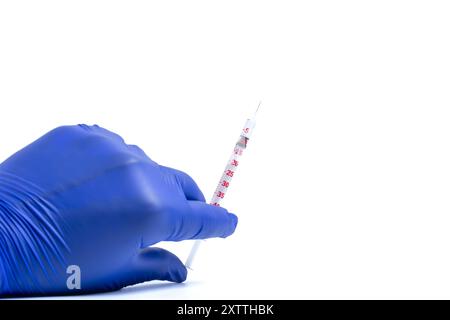 Hand des Arztes oder der Krankenschwester in blauen Handschuhen, die die Impfspritze auf weißem Hintergrund halten. Impfkonzept Stockfoto