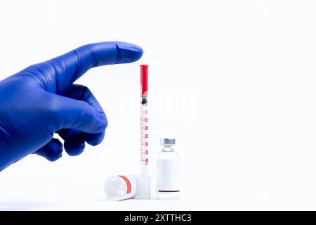 Medizinische Fläschchen und Spritze mit blauen Handschuhen auf weißem Hintergrund mit Kopierraum für Text Stockfoto