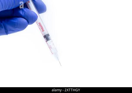 Arzt in blauen Handschuhen, die Spritze auf weißem Hintergrund mit Kopierraum halten Stockfoto