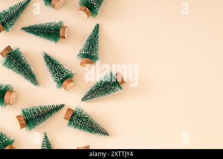 Trendiges Weihnachtsmuster mit grünen Weihnachtsbäumen auf pastellfarbenem cremefarbenen Hintergrund. Minimales kreatives Weihnachts- und Neujahrskonzept. Festliche Feiertage Stockfoto