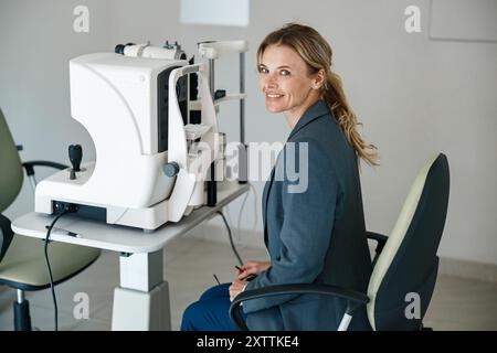 Lächelnde Patientin wartet auf einen Sehtest im Augenoptikgeschäft oder in der Augenklinik Stockfoto