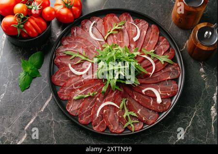 Marmor-Rindfleisch-Carpaccio auf einem schwarzen Teller Stockfoto