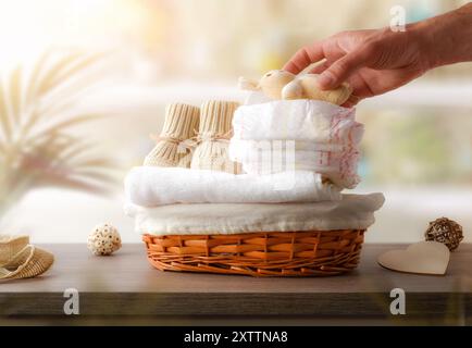 Handblättchen gefüllte Puppe auf Windeln und Tüchern und frisch gewaschene Babykleidung zum Wechseln auf Holzschrank mit Dekoration im Waschraum. Von Stockfoto