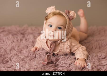 Vorderansicht eines kleinen Mädchens mit rosa Haube und Strampler Stockfoto