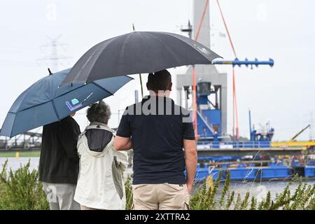 Elsfleth, Deutschland. August 2024. Die Familie Wallinger wirft trotz Regen einen Blick auf die Brückenbaustelle. Der „Athlet“-Schwimmkran bringt den 24 Meter langen, 58 Tonnen schweren Brückenabschnitt als Ersatz für die Eisenbahnbrücke, die einige Wochen zuvor von einem Tankfahrzeug gerammt wurde. Diese Brücke war auch eine provisorische Brücke, da bereits im Februar ein Lastkahn auf die reguläre Eisenbahnbrücke traf. Die Brücke und die Freileitungen wurden so stark beschädigt, dass der Zugverkehr eingestellt werden musste. Quelle: Lars Penning/dpa/Alamy Live News Stockfoto