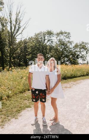 Lächelndes junges Paar, das zusammen auf einem Weg mit Wildblumen steht Stockfoto