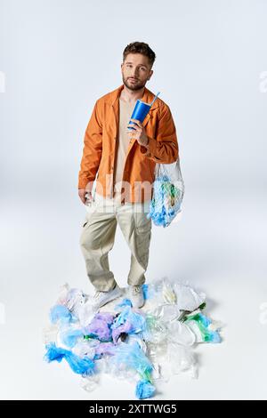 Mann auf Plastikberg mit blauem Becher und Plastiktüte. Stockfoto