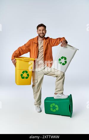 Ein Mann steht stolz mit Recyclingbehältern und zeigt sein Engagement für eine nachhaltige Zukunft. Stockfoto
