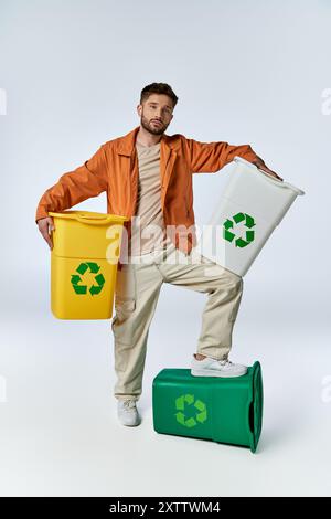 Ein Mann steht auf einem Recyclingbehälter, hält zwei weitere, umgeben von einem weißen Hintergrund. Stockfoto