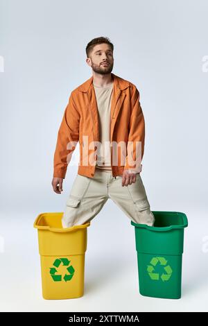 Ein Mann in einer orangefarbenen Jacke steckt mit seinen Beinen in zwei Mülltonnen fest. Stockfoto