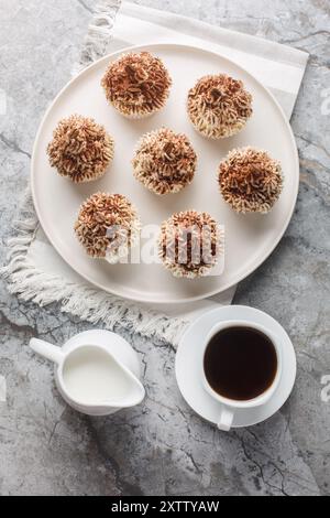 Delikate Tiramisu Cupcakes mit cremiger Mascarponcreme und Kakao serviert mit Kaffee in Nahaufnahme auf einem Teller auf einem Tisch. Vertikale Draufsicht von abo Stockfoto