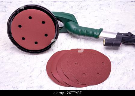 Wandschleifer mit Teleskopgriff und LED-Licht und Schleifpapier zum Glätten und Schleifen von Wänden auf grauweißem Hintergrund. Stockfoto