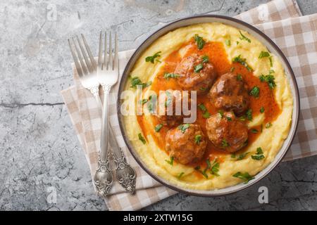 Gebackener Maisbrei mit Fleischbällchen und scharfer Soße in einer Schüssel auf dem Tisch. Horizontale Draufsicht von oben Stockfoto