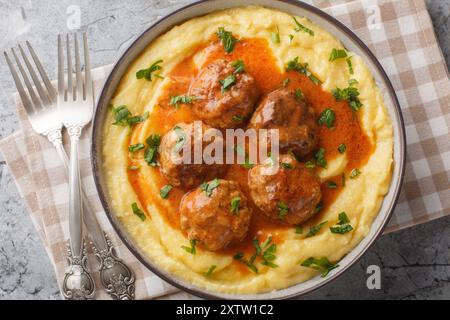 Frittierte Fleischbällchen mit scharfer Soße und Maispolenta in einer Schüssel auf dem Tisch. Horizontale Draufsicht von oben Stockfoto