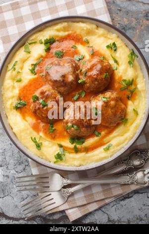 Cremige Polenta und Fleischbällchen mit Soße in der Schüssel auf dem Tisch. Vertikale Draufsicht von oben Stockfoto