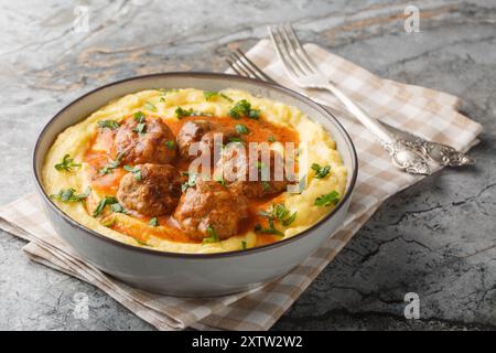 Gebackener Maisbrei mit Fleischbällchen und scharfer Soße in einer Schüssel auf dem Tisch. Horizontal Stockfoto