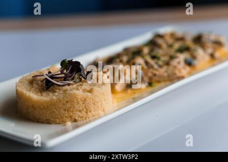 Couscous-Brei mit Fleisch- und Pilzsauce auf einer weißen Keramikplatte Stockfoto