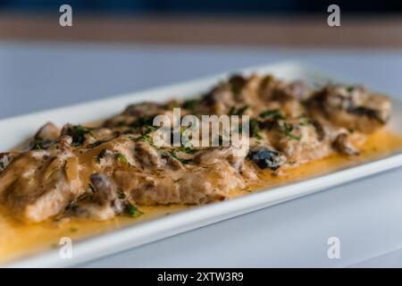 Couscous-Brei mit Fleisch- und Pilzsauce auf einer weißen Keramikplatte Stockfoto