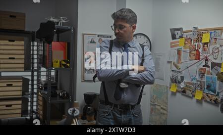 Ein junger hispanischer Mann steht im Büro eines Detektivs mit einer Beweisführung hinter sich. Stockfoto