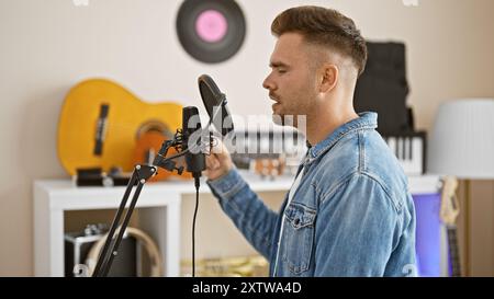 Ein junger hispanischer Mann singt in einem Musikstudio in ein Mikrofon und zeigt künstlerisches Talent und Kreativität. Stockfoto