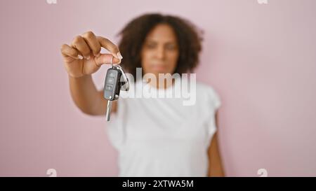 afroamerikanerin, die Autoschlüssel vor rosafarbenem Hintergrund hält Stockfoto